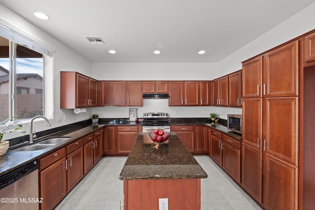 kitchen with appliances with stainless steel finishes, a center island, sink, and dark stone counters