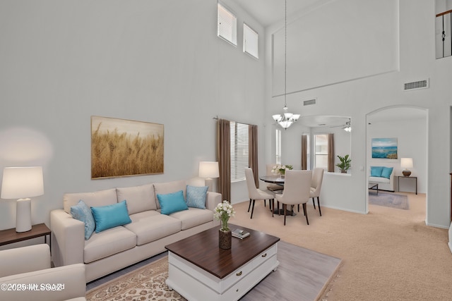 carpeted living room with ceiling fan with notable chandelier