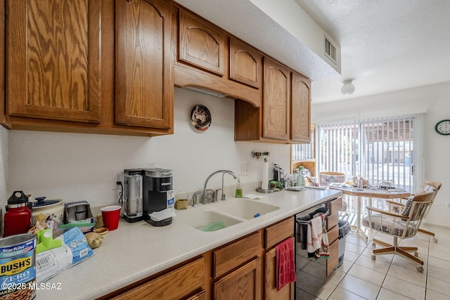 kitchen featuring light tile patterned flooring, dishwasher, sink, and a textured ceiling