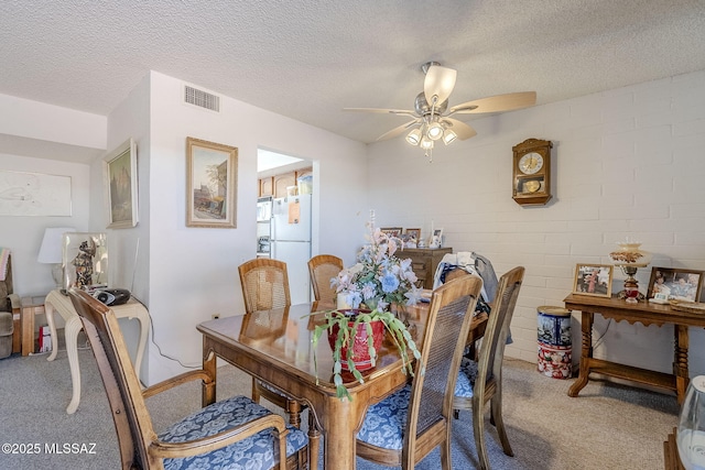 carpeted dining room with ceiling fan and a textured ceiling