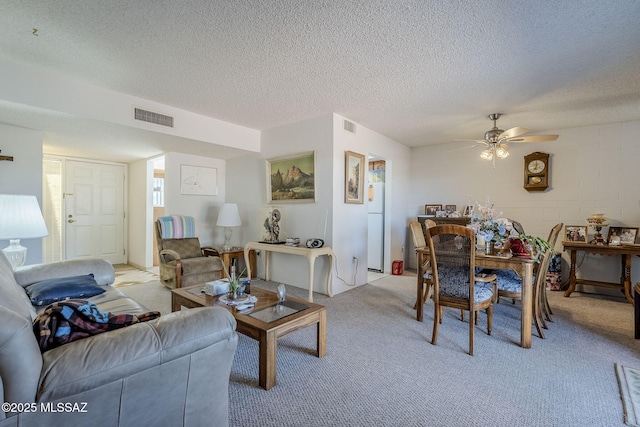 living room featuring ceiling fan, light colored carpet, and a textured ceiling