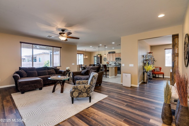 living room featuring dark wood-type flooring and ceiling fan