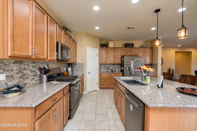 kitchen featuring hanging light fixtures, a kitchen island with sink, light tile patterned floors, stainless steel appliances, and light stone countertops