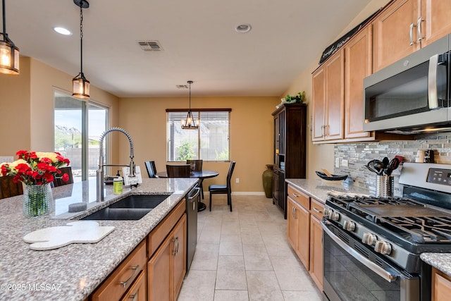 kitchen featuring appliances with stainless steel finishes, pendant lighting, tasteful backsplash, sink, and light stone counters