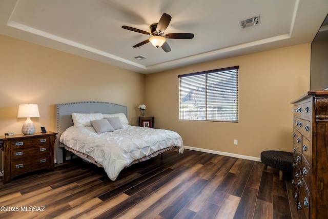 bedroom featuring dark hardwood / wood-style floors, ceiling fan, and a tray ceiling