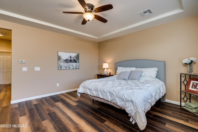 bedroom with dark hardwood / wood-style floors, ceiling fan, and a tray ceiling