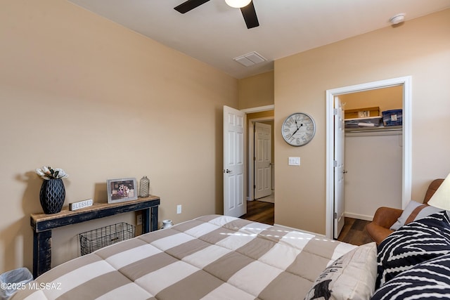 bedroom featuring a walk in closet, dark hardwood / wood-style floors, ceiling fan, and a closet