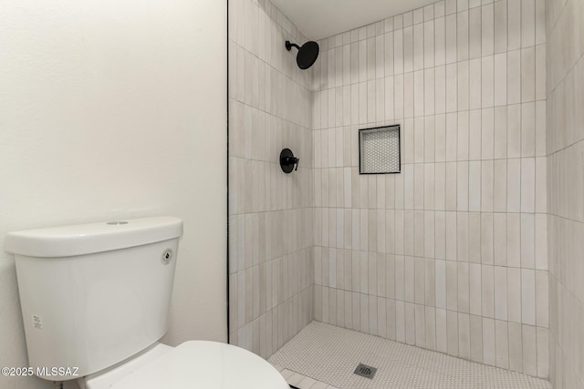 bathroom featuring a tile shower and toilet