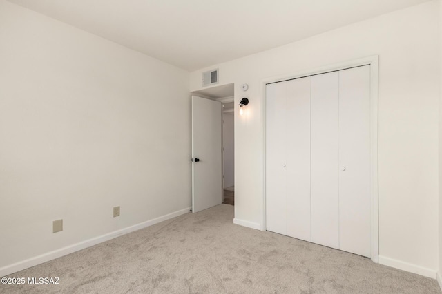 unfurnished bedroom featuring light carpet and a closet