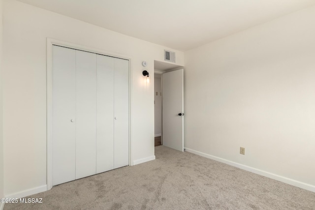 unfurnished bedroom featuring light colored carpet and a closet