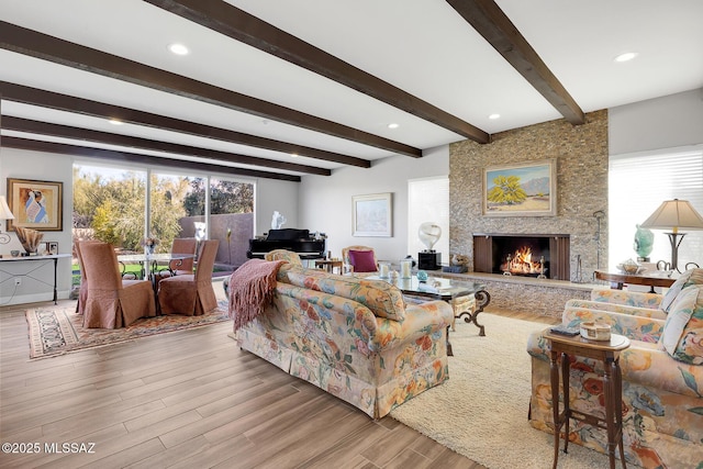 living room featuring beam ceiling, a fireplace, and light wood-type flooring