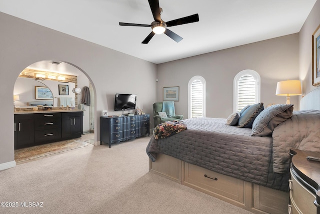 bedroom featuring light carpet, ceiling fan, and ensuite bathroom