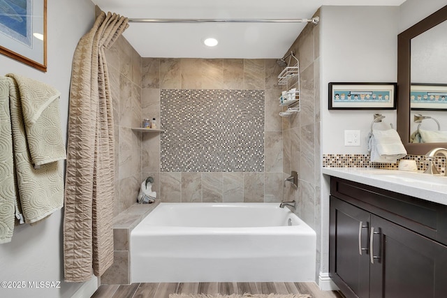 bathroom with tasteful backsplash, wood-type flooring, tiled shower / bath combo, and vanity