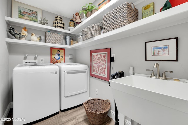 clothes washing area with sink, independent washer and dryer, and light hardwood / wood-style floors