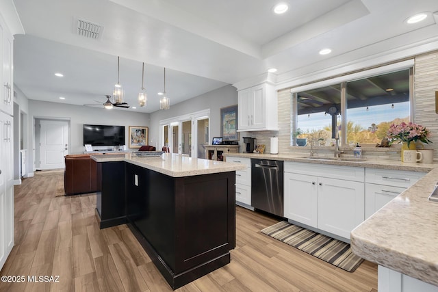 kitchen featuring sink, stainless steel dishwasher, a kitchen island, pendant lighting, and white cabinets