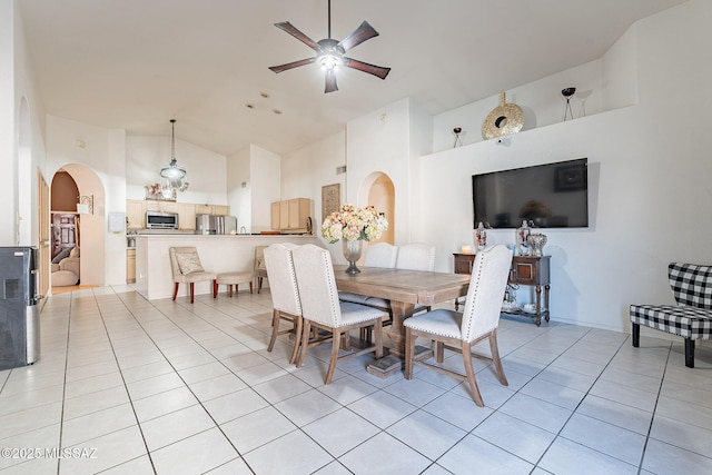 dining space featuring light tile patterned floors, arched walkways, and high vaulted ceiling