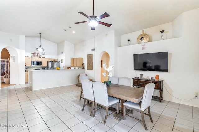 dining space featuring light tile patterned floors, ceiling fan, arched walkways, and high vaulted ceiling