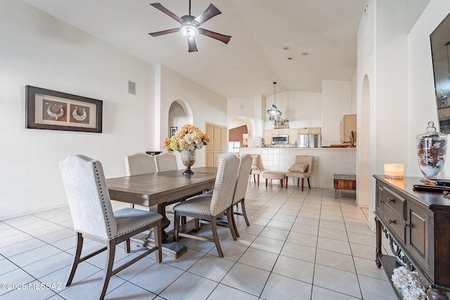 dining space featuring arched walkways, ceiling fan, light tile patterned floors, and high vaulted ceiling