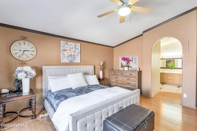 bedroom featuring arched walkways, ensuite bathroom, lofted ceiling, wood finished floors, and crown molding