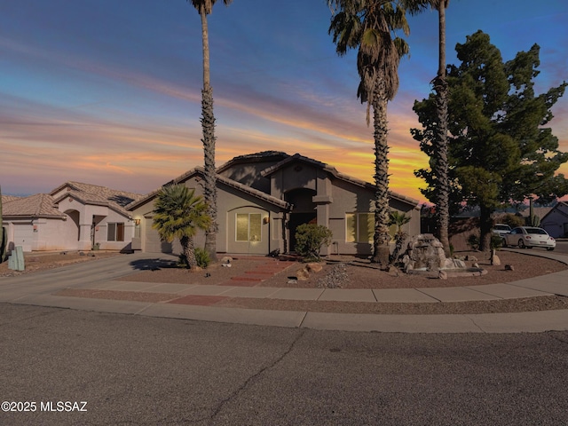 view of front of house with an attached garage, concrete driveway, and stucco siding