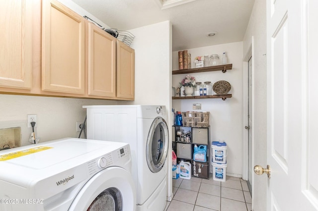 washroom featuring cabinet space, washing machine and clothes dryer, and light tile patterned floors