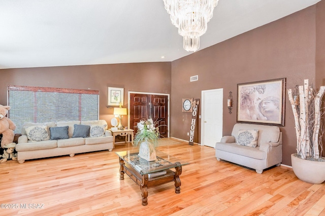 living area featuring wood finished floors, visible vents, baseboards, vaulted ceiling, and an inviting chandelier