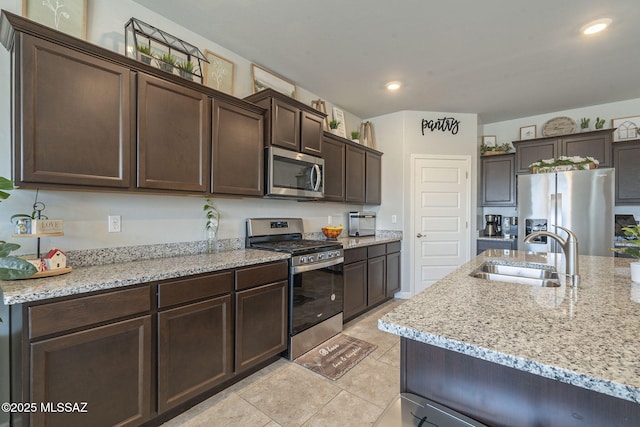 kitchen featuring appliances with stainless steel finishes, sink, light stone counters, and dark brown cabinets