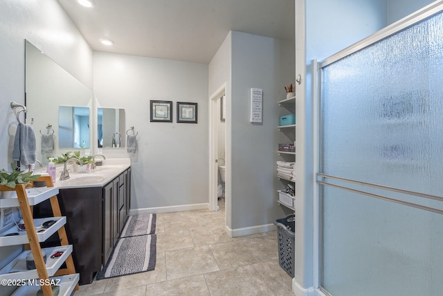 bathroom featuring tile patterned flooring, vanity, toilet, and walk in shower