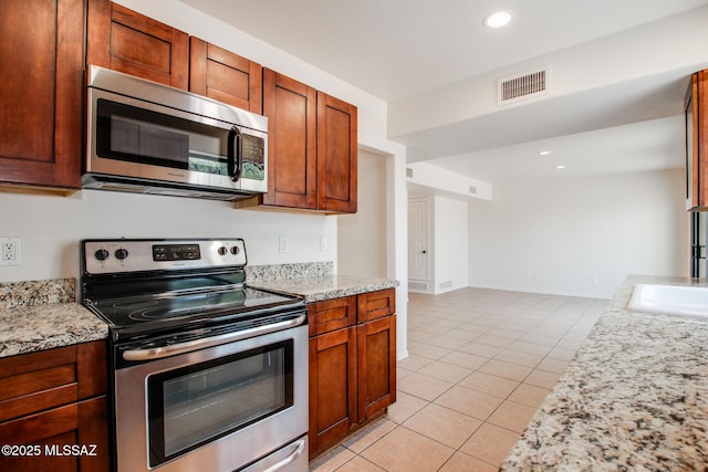 kitchen with sink, light stone countertops, stainless steel appliances, and light tile patterned floors