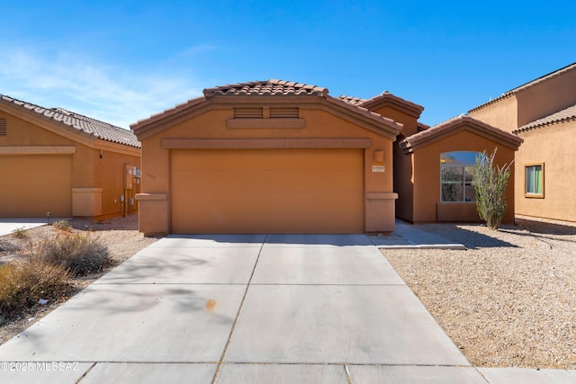 mediterranean / spanish house with a garage, driveway, and stucco siding