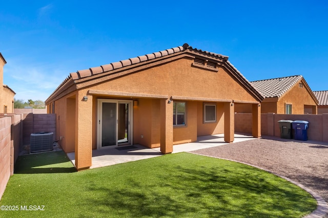 back of house featuring a yard, a patio, stucco siding, central AC unit, and a fenced backyard