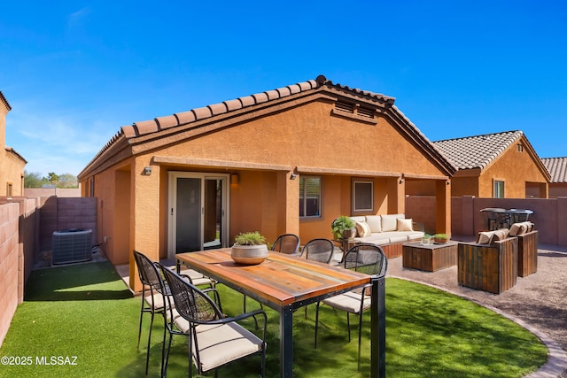 back of property with a yard, stucco siding, outdoor lounge area, central AC, and a fenced backyard