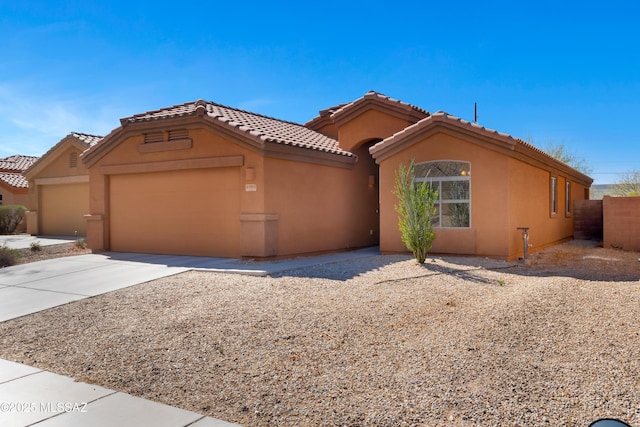 view of front facade with concrete driveway, a tile roof, an attached garage, and stucco siding