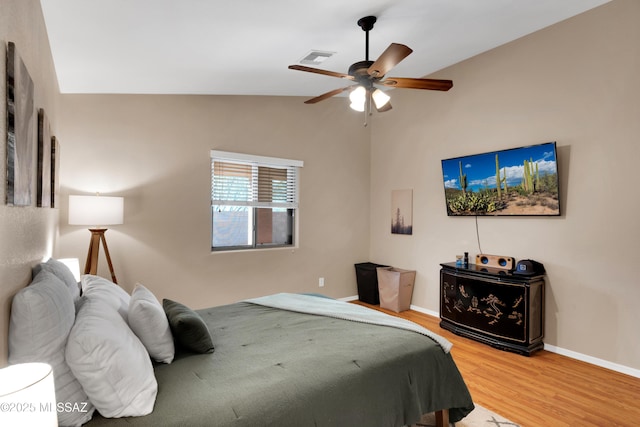 bedroom featuring lofted ceiling, ceiling fan, wood finished floors, visible vents, and baseboards