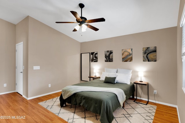 bedroom featuring a ceiling fan, vaulted ceiling, baseboards, and wood finished floors