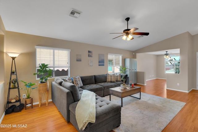 living room featuring light wood-style flooring, visible vents, vaulted ceiling, and baseboards