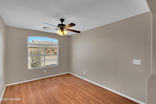 spare room with light wood-type flooring, baseboards, visible vents, and ceiling fan