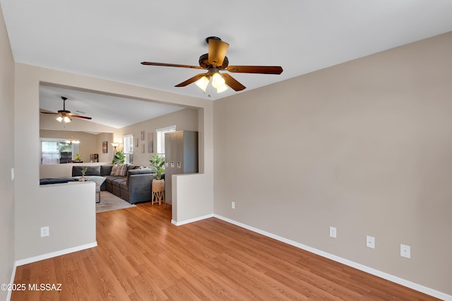 spare room featuring a ceiling fan, light wood-type flooring, lofted ceiling, and baseboards