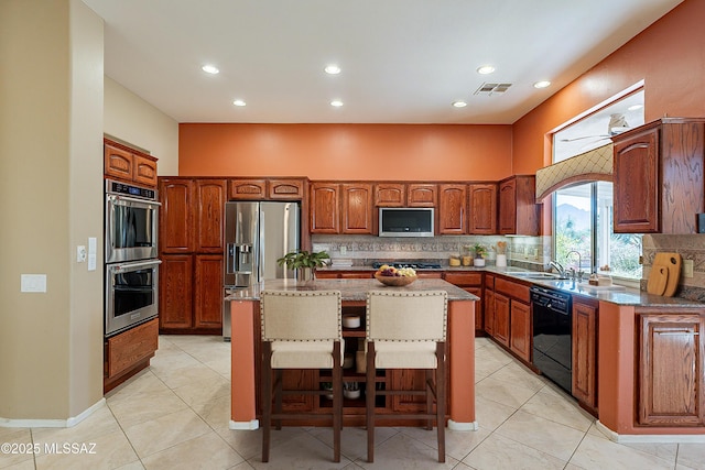 kitchen with backsplash, a kitchen bar, a center island, and black appliances