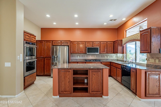 kitchen with sink, dark stone countertops, backsplash, a center island, and black appliances