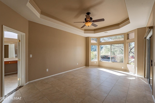 unfurnished room with light tile patterned floors, a raised ceiling, and ceiling fan