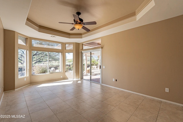 empty room with light tile patterned floors, a raised ceiling, and ceiling fan