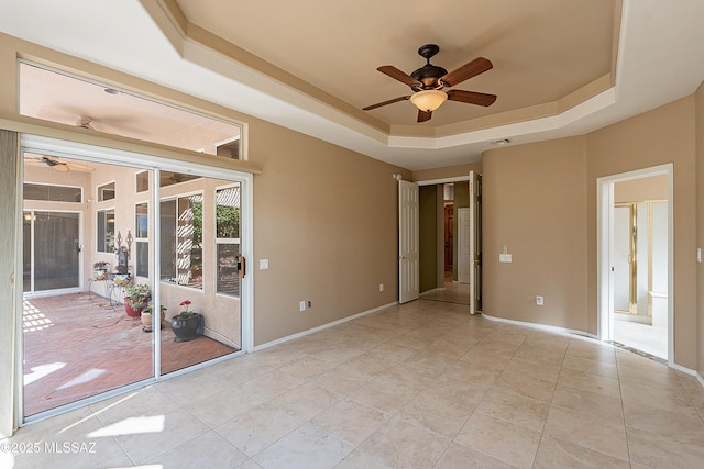 unfurnished room featuring light tile patterned floors, a raised ceiling, and ceiling fan