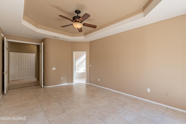 spare room featuring a raised ceiling and ceiling fan