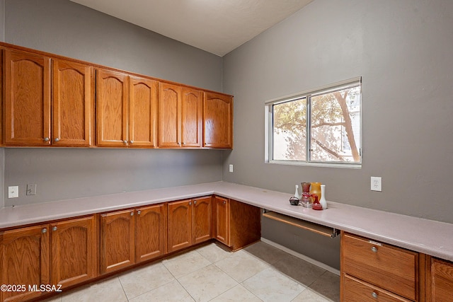 unfurnished office featuring light tile patterned floors and built in desk