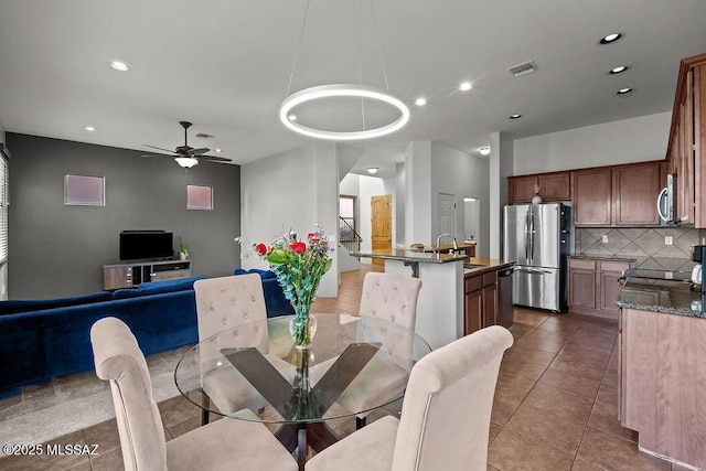 dining area featuring sink, dark tile patterned floors, and ceiling fan