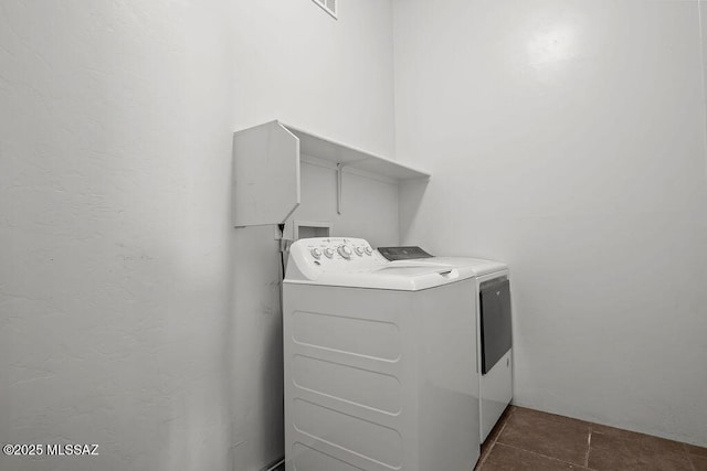 laundry area featuring washer and clothes dryer and dark tile patterned floors