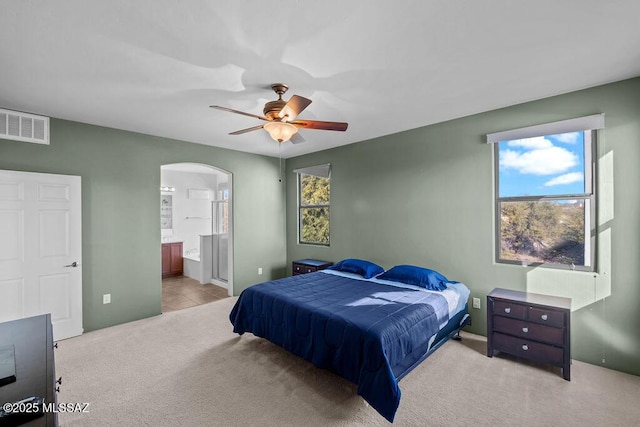 carpeted bedroom with ceiling fan and ensuite bath