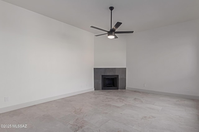 unfurnished living room with a tiled fireplace and ceiling fan