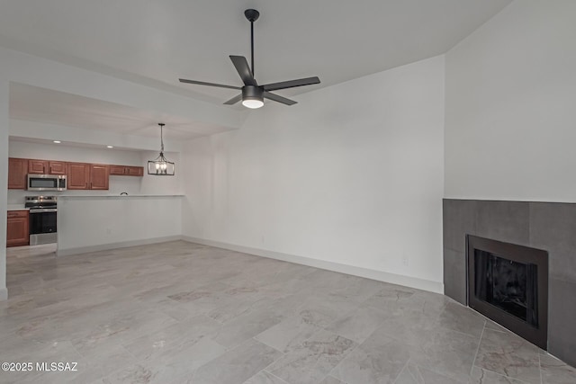 unfurnished living room with ceiling fan with notable chandelier and a fireplace